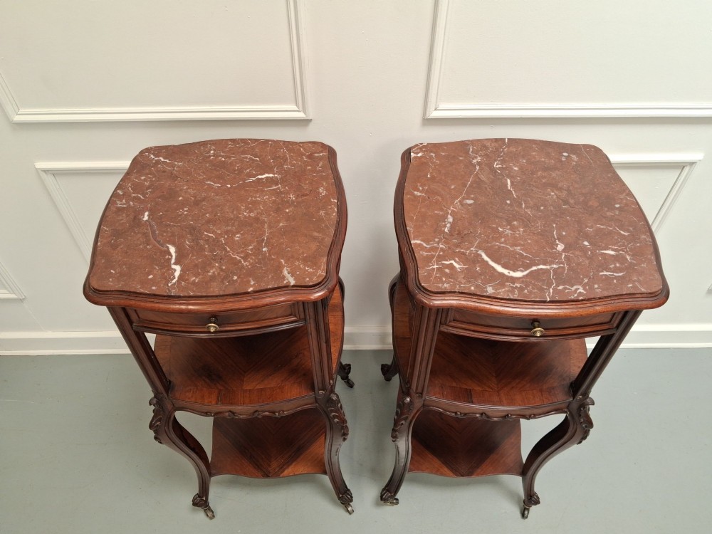 A matching pair of tall dark wood end tables featuring top drawers, lower open shelves, carved cabriole legs, and brass castors. View IX