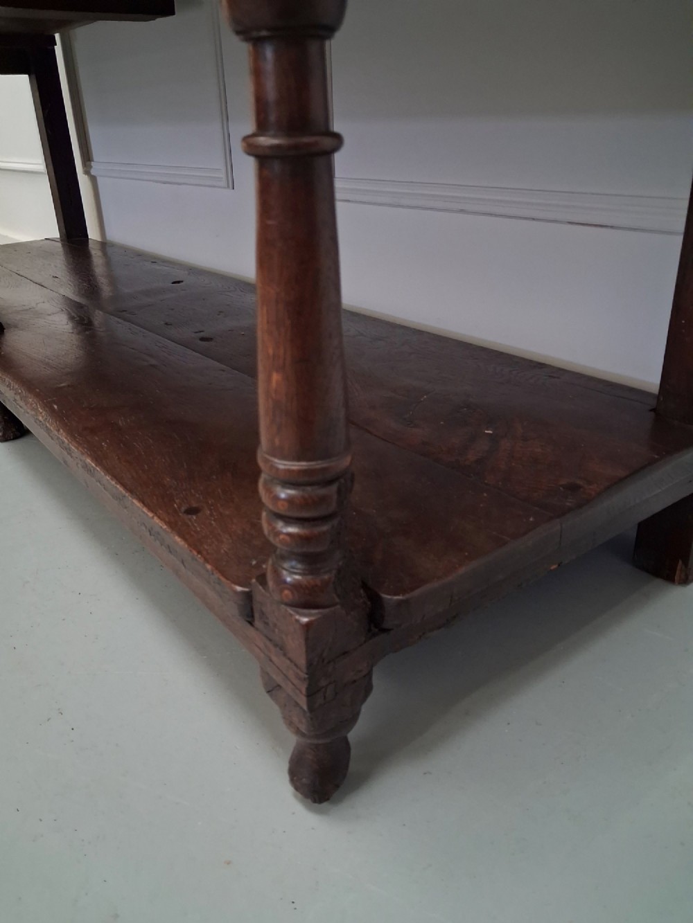 An 18th-century dark oak Georgian dresser base featuring three drawers with brass handles, turned front legs, and a low pot board shelf. View VI