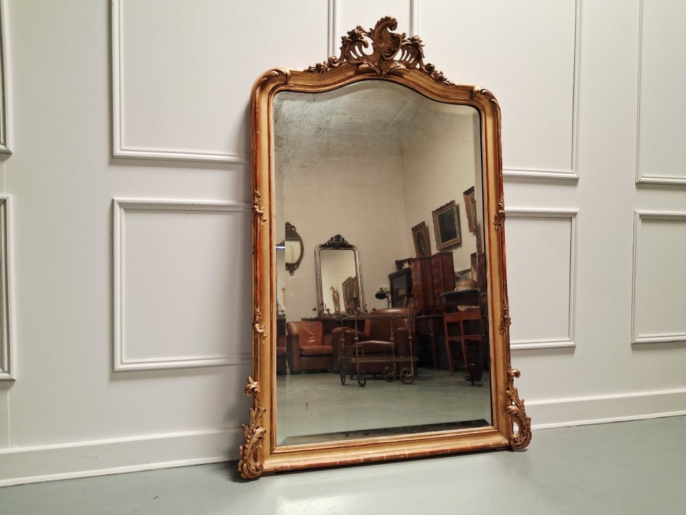 A large nineteenth-century French Rococo giltwood wall mirror with an arched top crested by an ornate shell and scroll carving.