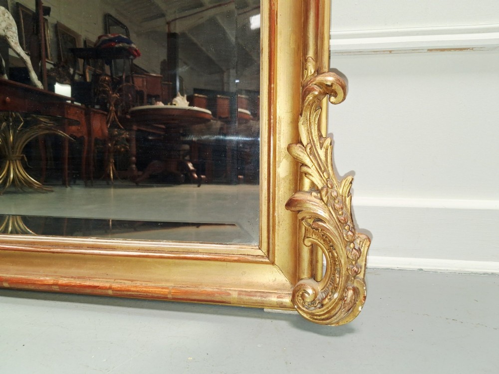 A large nineteenth-century French Rococo giltwood wall mirror with an arched top crested by an ornate shell and scroll carving. View III