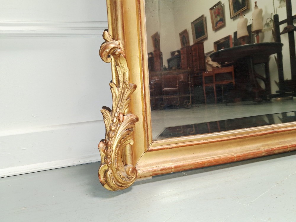 A large nineteenth-century French Rococo giltwood wall mirror with an arched top crested by an ornate shell and scroll carving. View IV