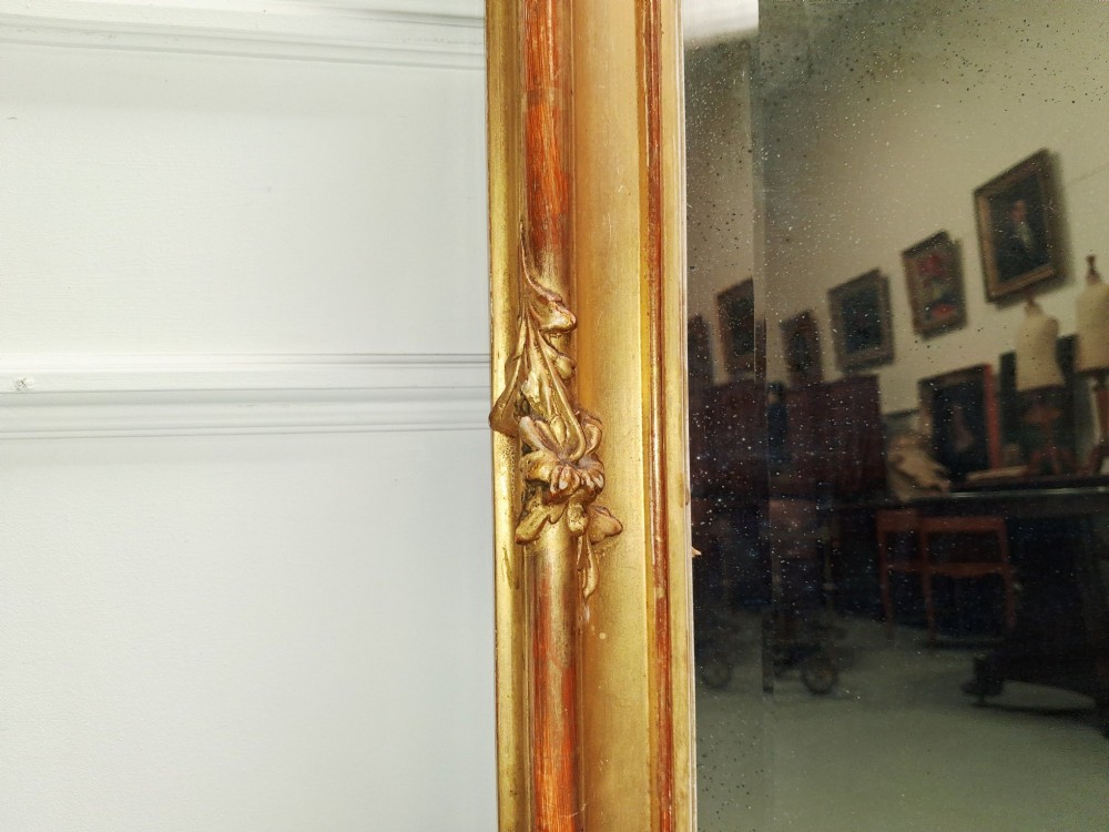 A large nineteenth-century French Rococo giltwood wall mirror with an arched top crested by an ornate shell and scroll carving. View V