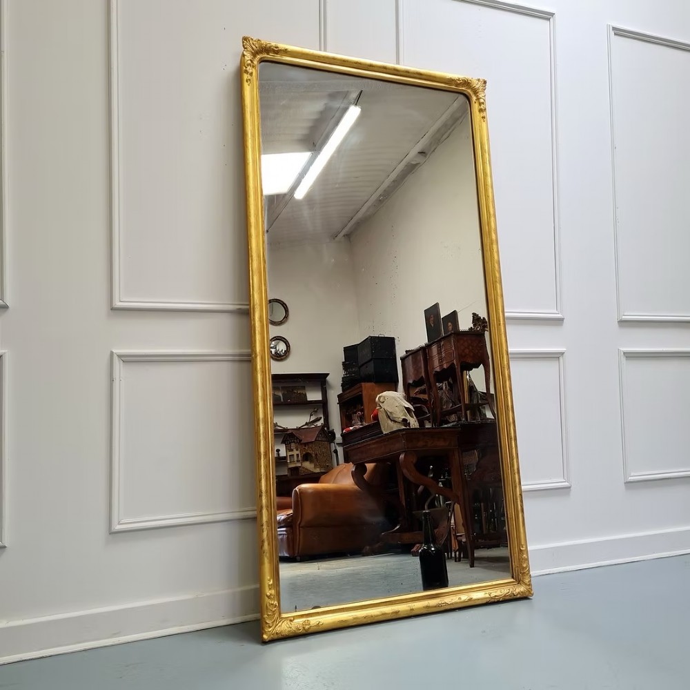 A tall rectangular French antique floor mirror featuring a gold gilded frame with rounded top corners and leaf details. View VII