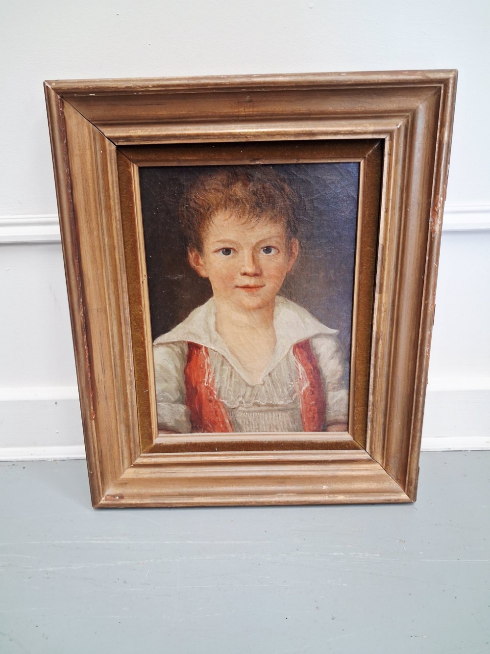A pair of 19th-century oil portrait paintings depicting a young girl and boy set inside wide moulded giltwood frames. View II