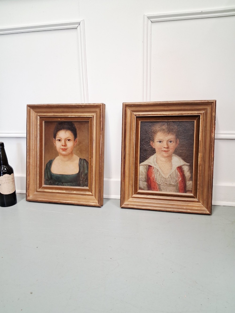A pair of 19th-century oil portrait paintings depicting a young girl and boy set inside wide moulded giltwood frames. View IV
