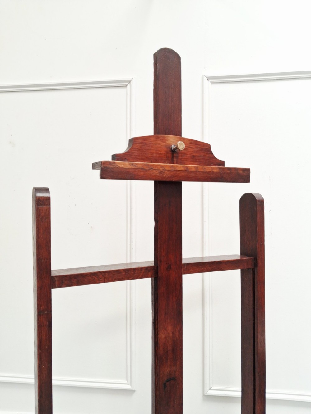 A tall dark oak studio easel featuring an adjustable central mast, upper clamp, solid lower shelf, and a heavy H-frame base. View II