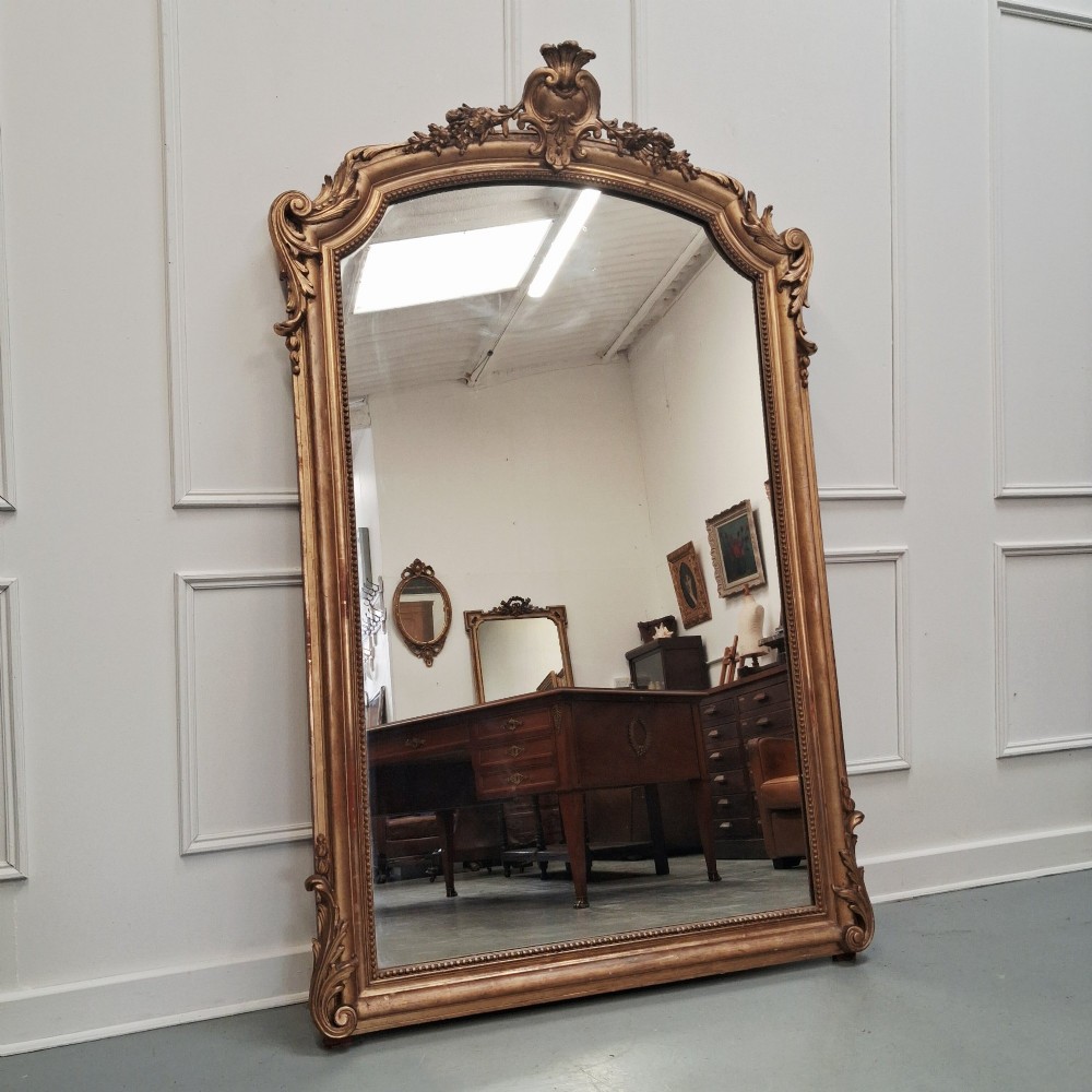 A large nineteenth-century French arched mirror with a gold giltwood frame and ornate carved floral cresting.