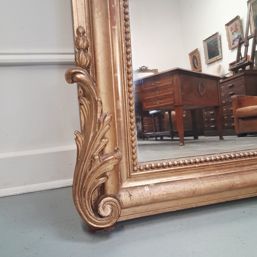 A large nineteenth-century French arched mirror with a gold giltwood frame and ornate carved floral cresting. View III