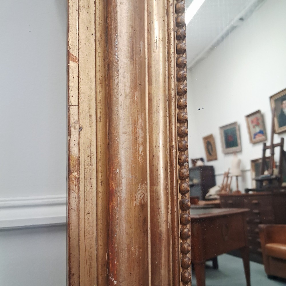 A large nineteenth-century French arched mirror with a gold giltwood frame and ornate carved floral cresting. View IV