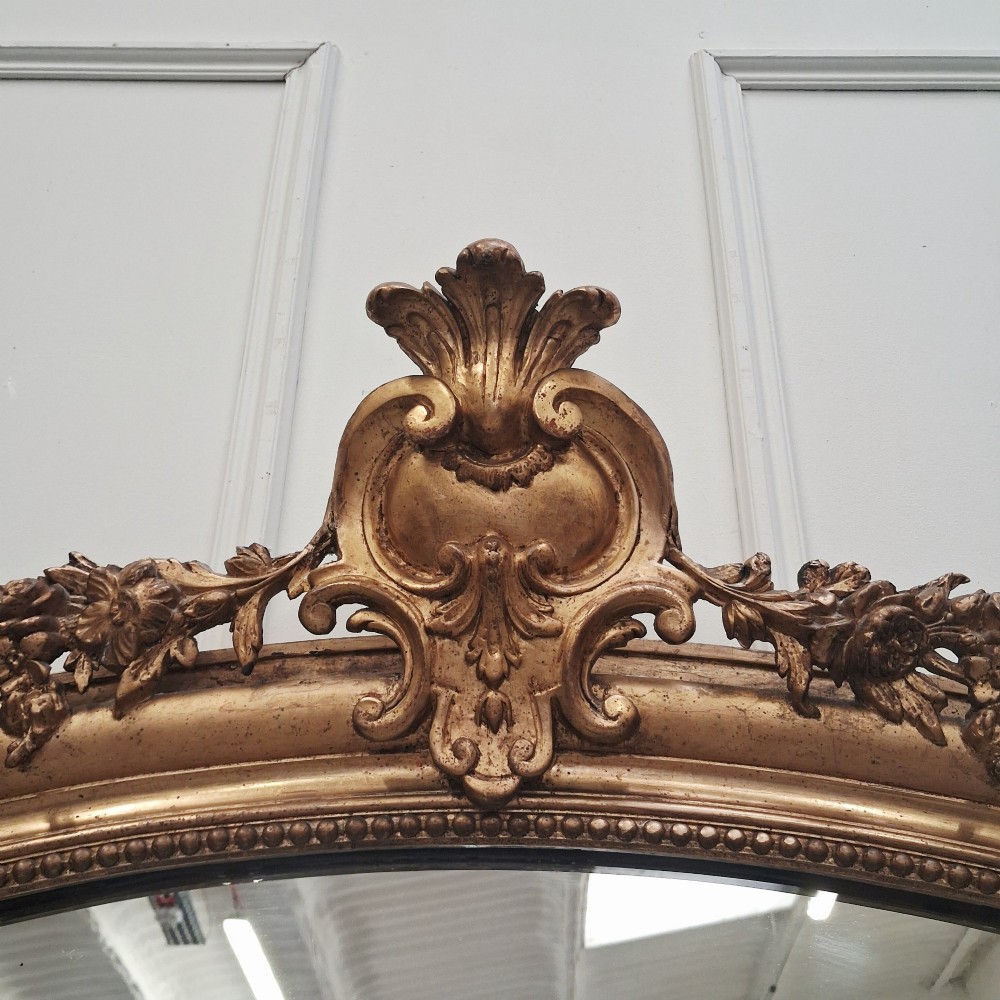 A large nineteenth-century French arched mirror with a gold giltwood frame and ornate carved floral cresting. View VI