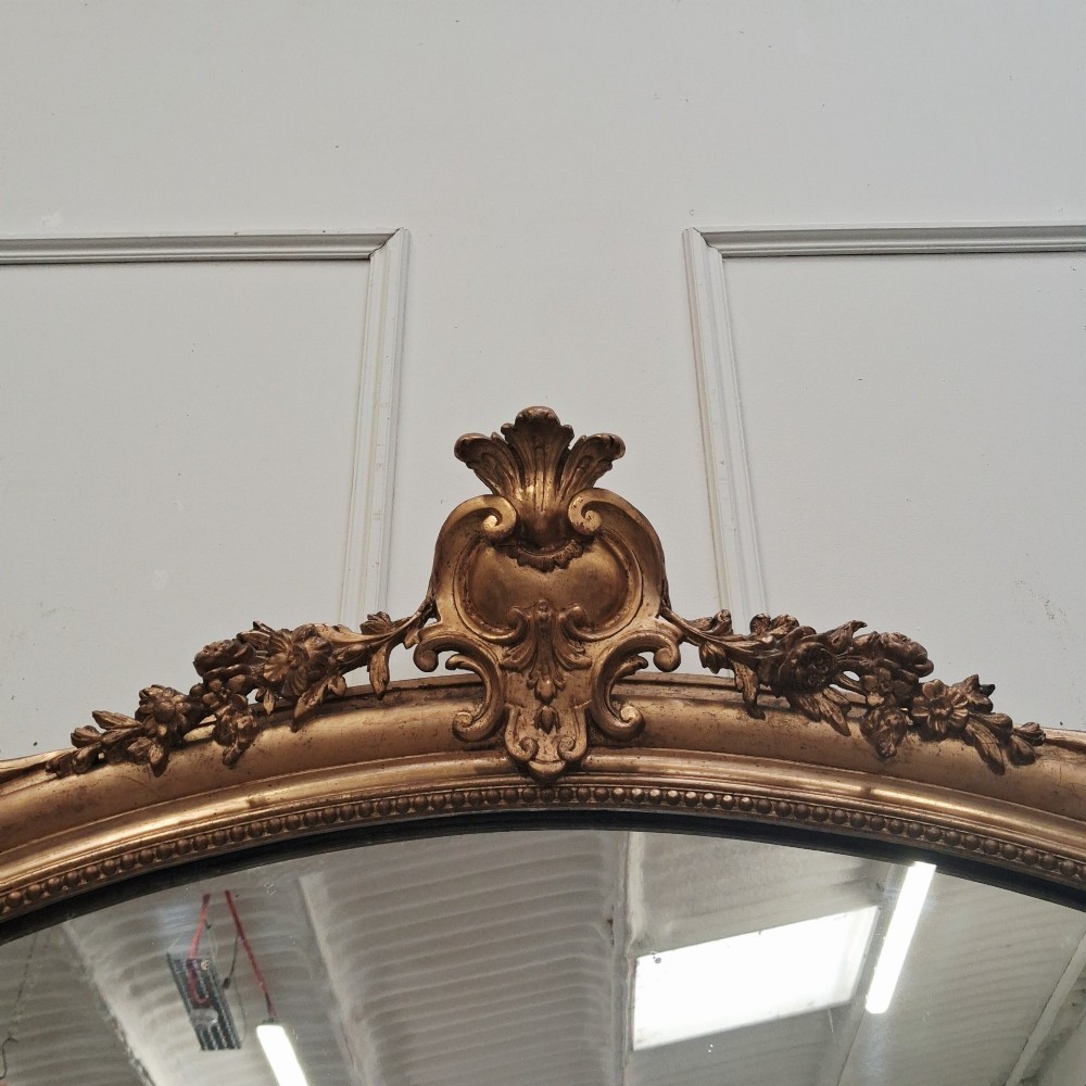 A large nineteenth-century French arched mirror with a gold giltwood frame and ornate carved floral cresting. View VII
