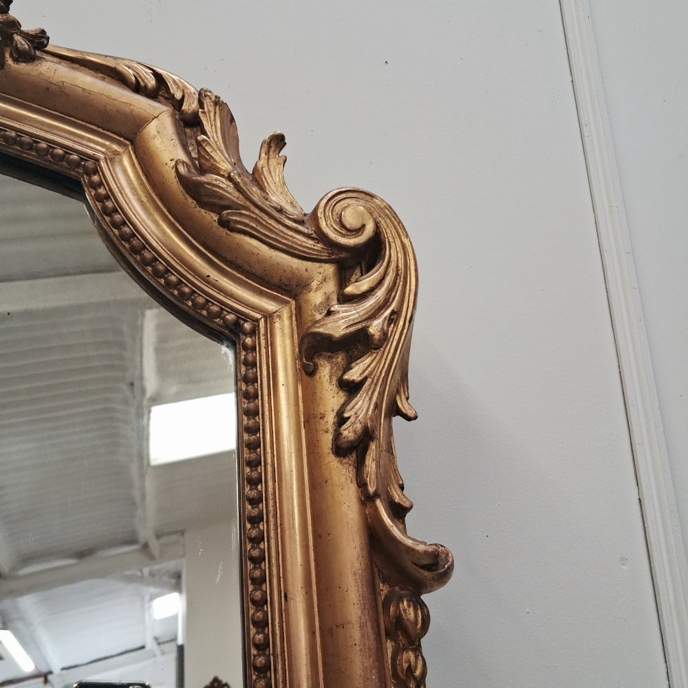 A large nineteenth-century French arched mirror with a gold giltwood frame and ornate carved floral cresting. View IX
