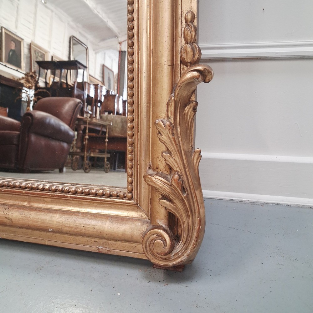 A large nineteenth-century French arched mirror with a gold giltwood frame and ornate carved floral cresting. View X