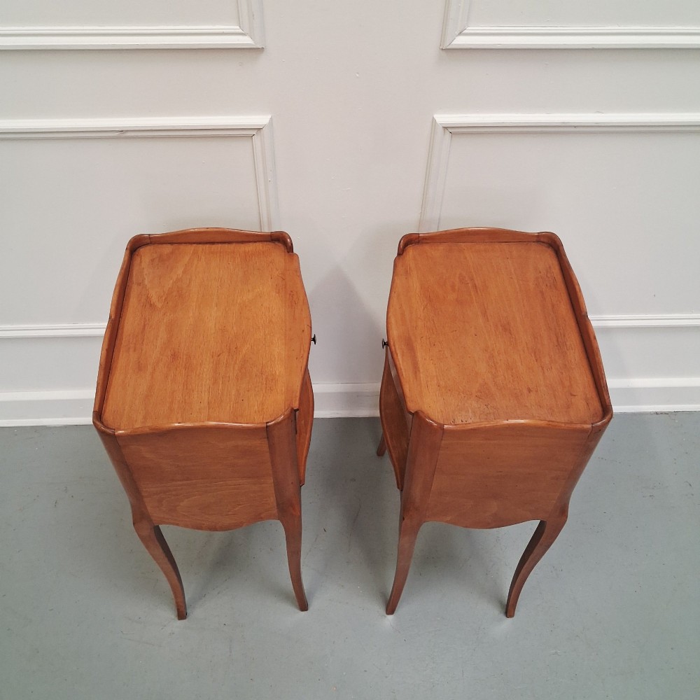 A pair of warm brown French bedside tables with slender cabriole legs, open shelf alcoves, single top drawers, and small metal knobs. View V