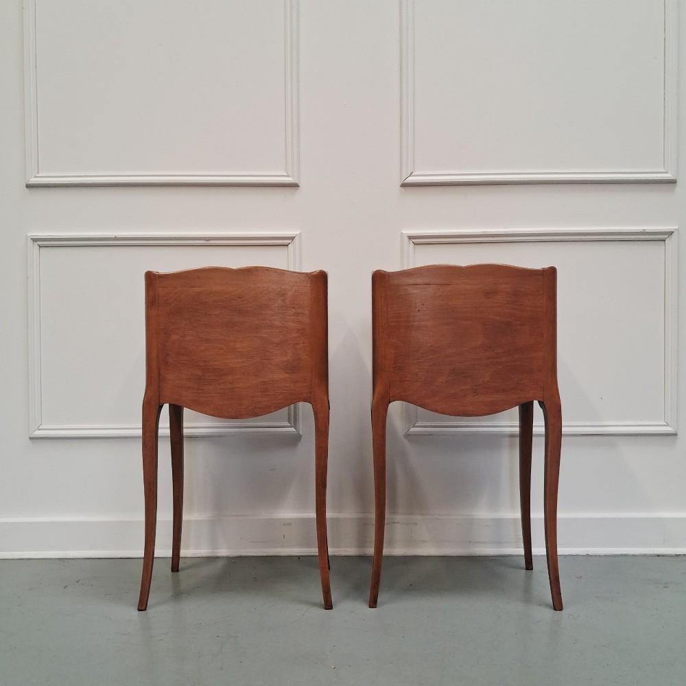 A pair of warm brown French bedside tables with slender cabriole legs, open shelf alcoves, single top drawers, and small metal knobs. View VI
