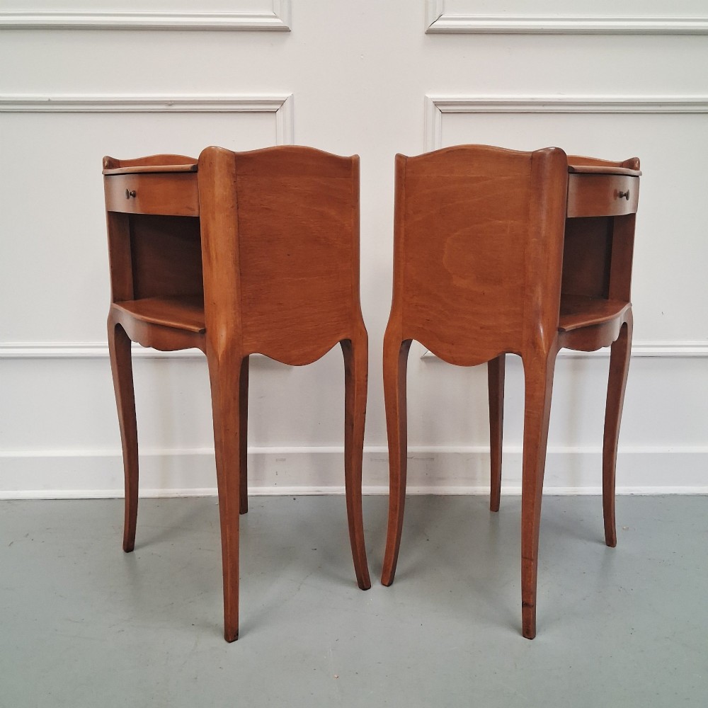 A pair of warm brown French bedside tables with slender cabriole legs, open shelf alcoves, single top drawers, and small metal knobs. View VII