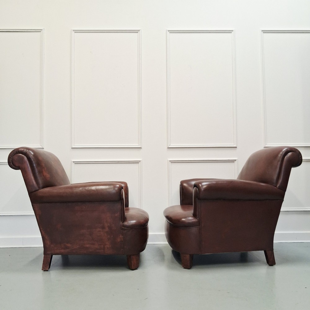 A pair of 1930s French club chairs upholstered in warm brown leather with rolled arms and short wooden feet. View II