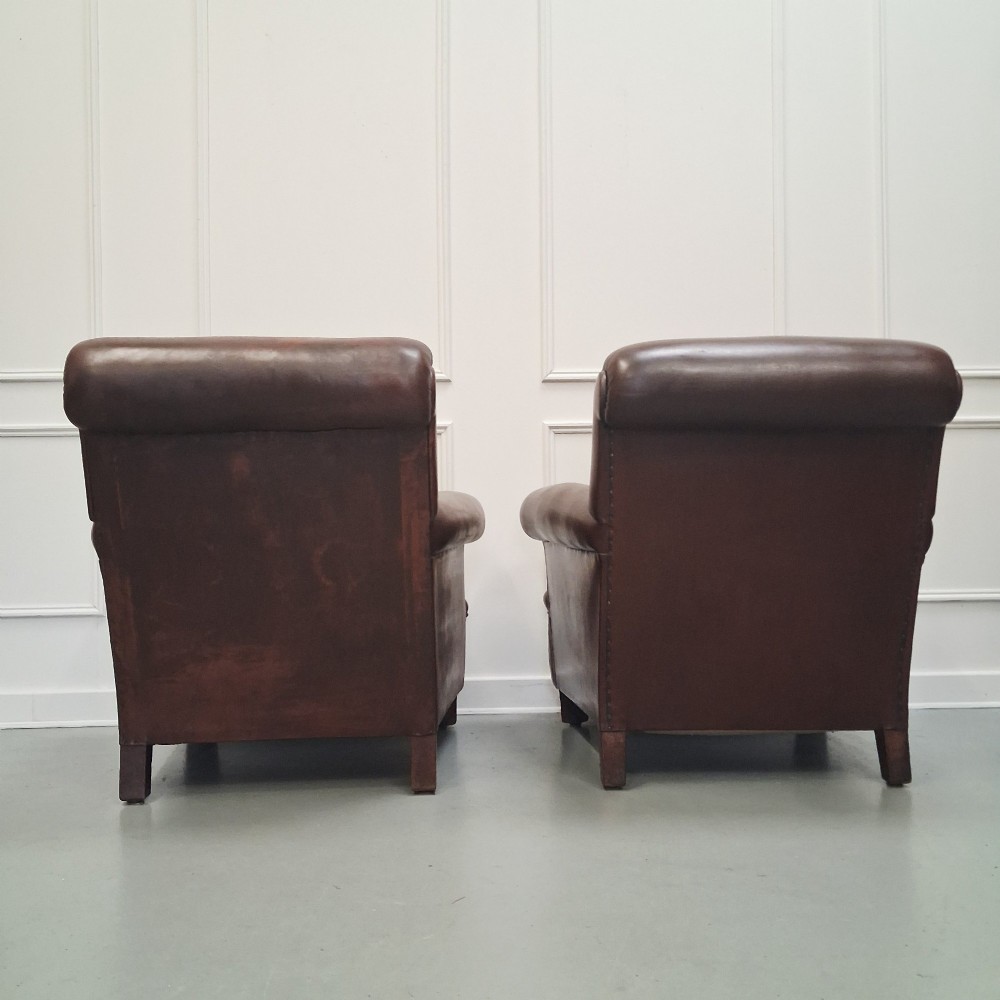 A pair of 1930s French club chairs upholstered in warm brown leather with rolled arms and short wooden feet. View III