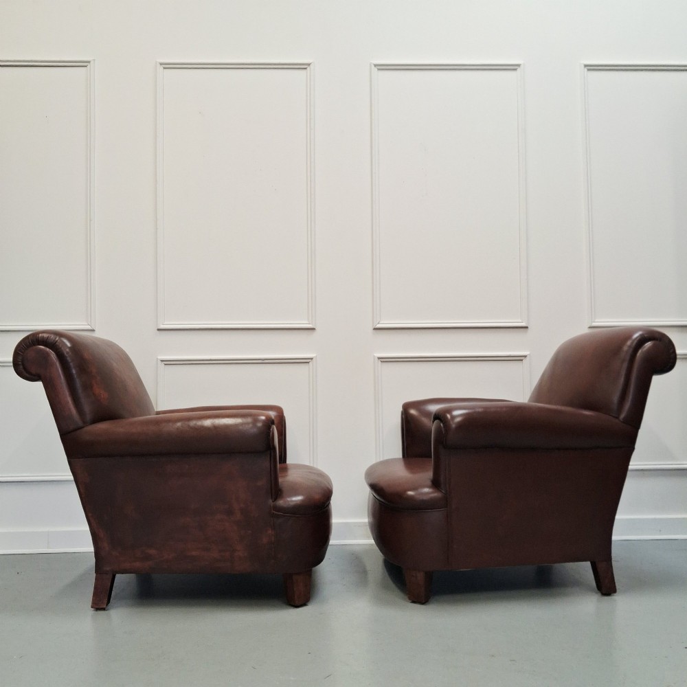 A pair of 1930s French club chairs upholstered in warm brown leather with rolled arms and short wooden feet. View IV