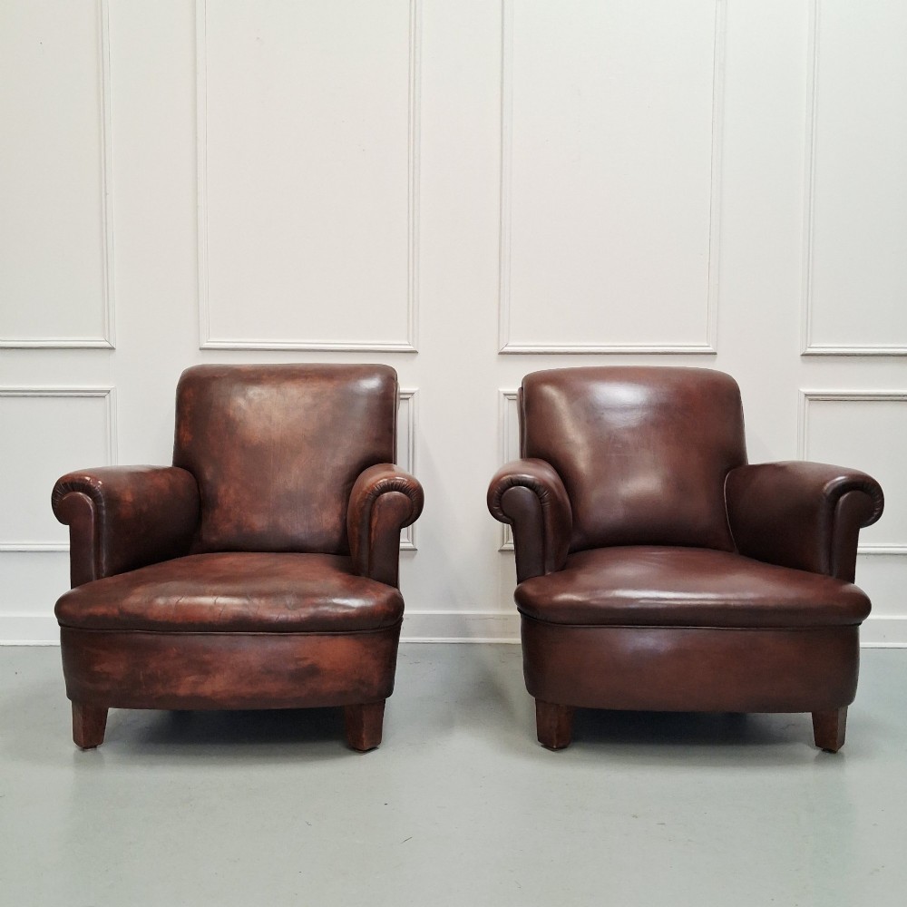 A pair of 1930s French club chairs upholstered in warm brown leather with rolled arms and short wooden feet. View VI