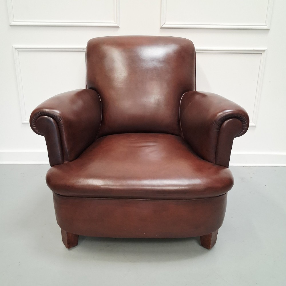 A pair of 1930s French club chairs upholstered in warm brown leather with rolled arms and short wooden feet. View IX