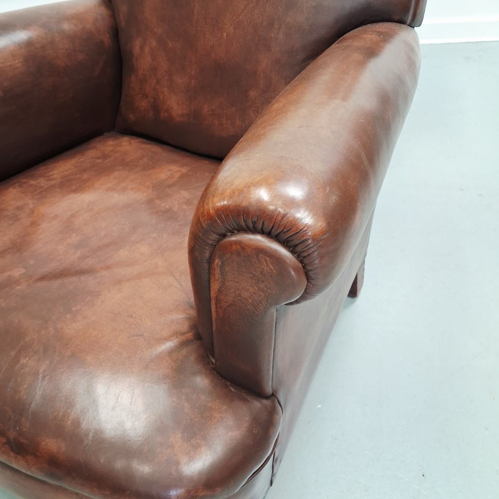 A pair of 1930s French club chairs upholstered in warm brown leather with rolled arms and short wooden feet. View XI