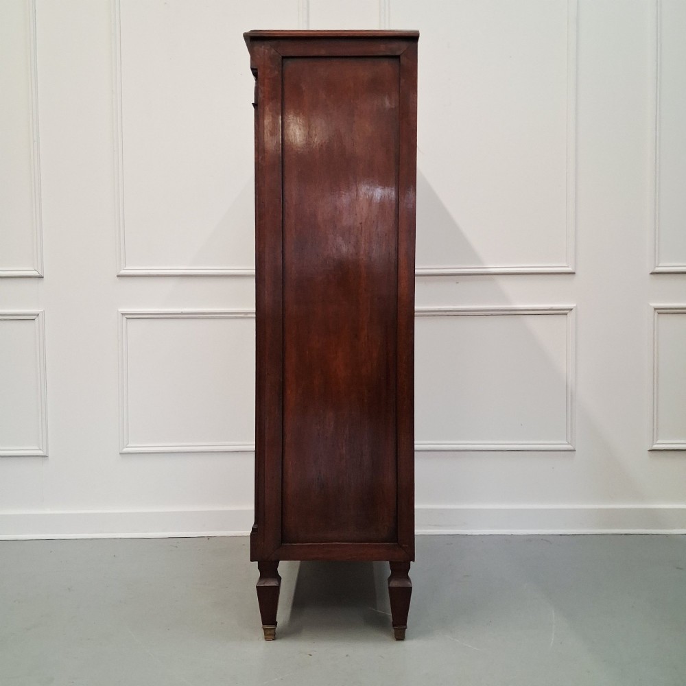 An antique French mahogany semainier tallboy featuring seven drawers with round brass pulls and diamond-shaped brass escutcheons set on short turned feet. View V