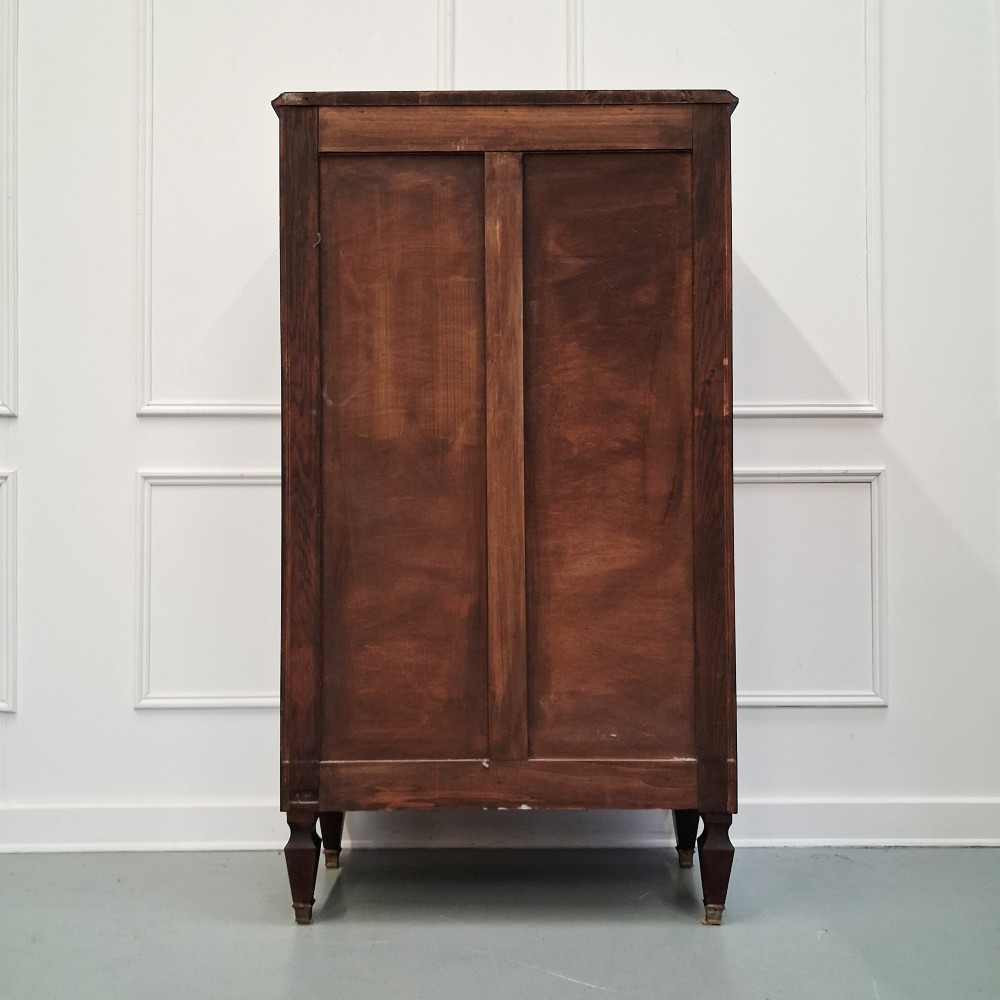 An antique French mahogany semainier tallboy featuring seven drawers with round brass pulls and diamond-shaped brass escutcheons set on short turned feet. View VI