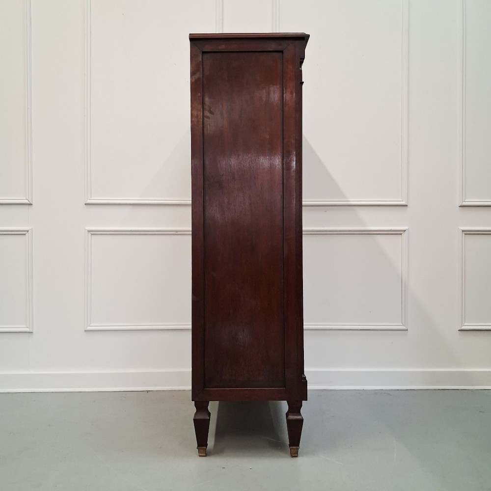 An antique French mahogany semainier tallboy featuring seven drawers with round brass pulls and diamond-shaped brass escutcheons set on short turned feet. View VII