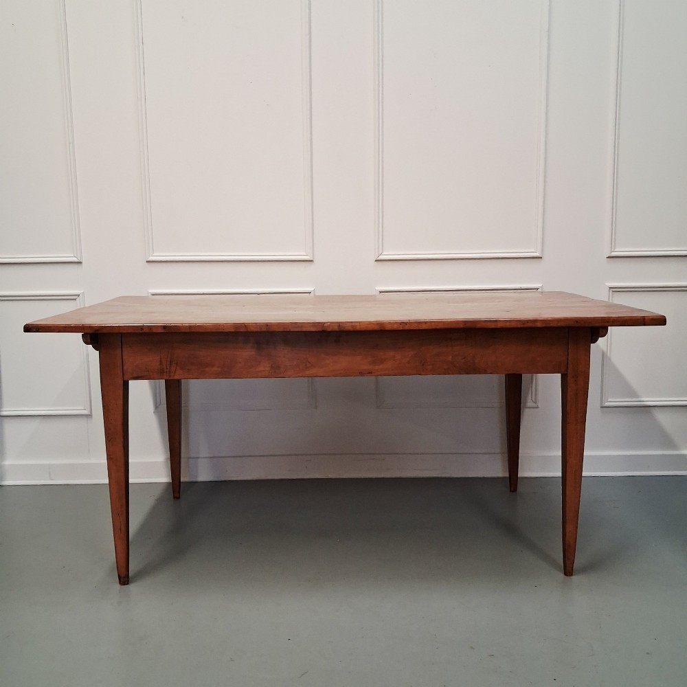 An antique 19th-century satin birch farmhouse table featuring a rectangular plank top, deep apron, and four square tapered legs.