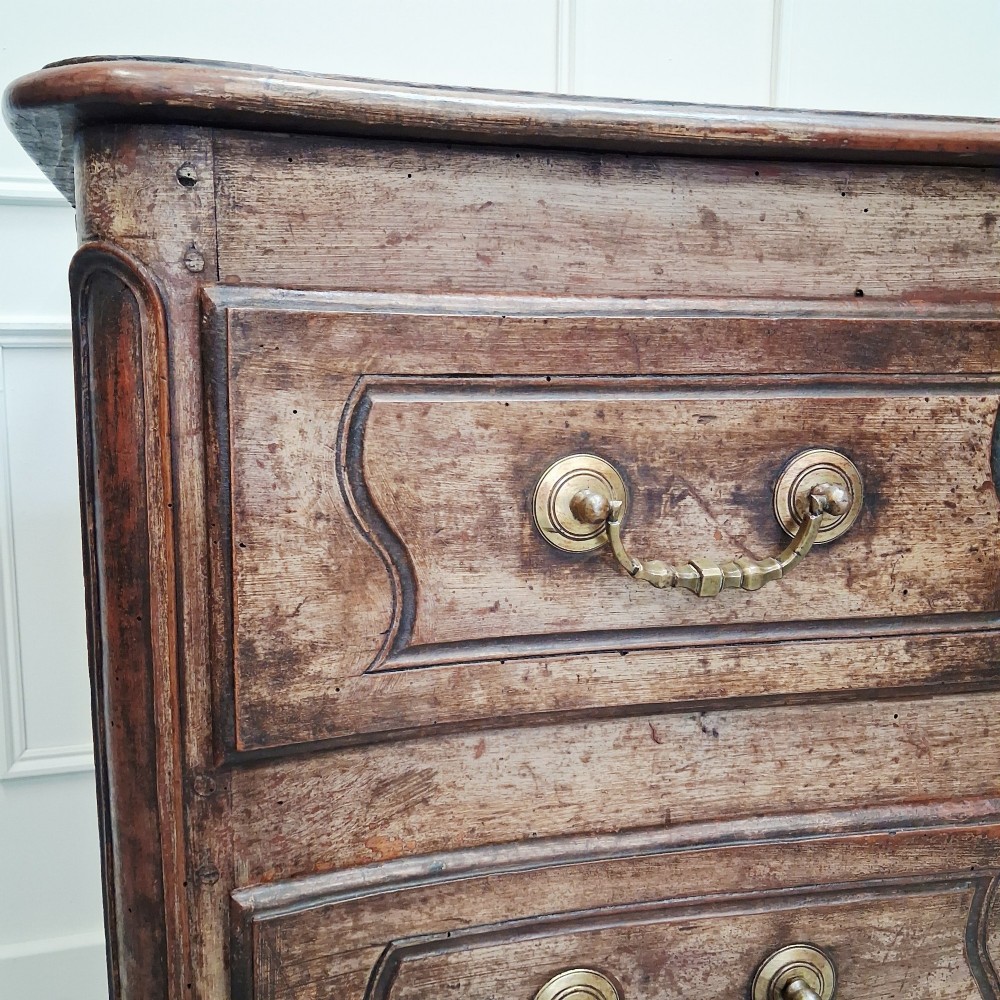An antique French oak commode featuring two wide drawers with carved moulded panel details, brass drop handles, a scalloped lower apron, and short cabriole feet. View II