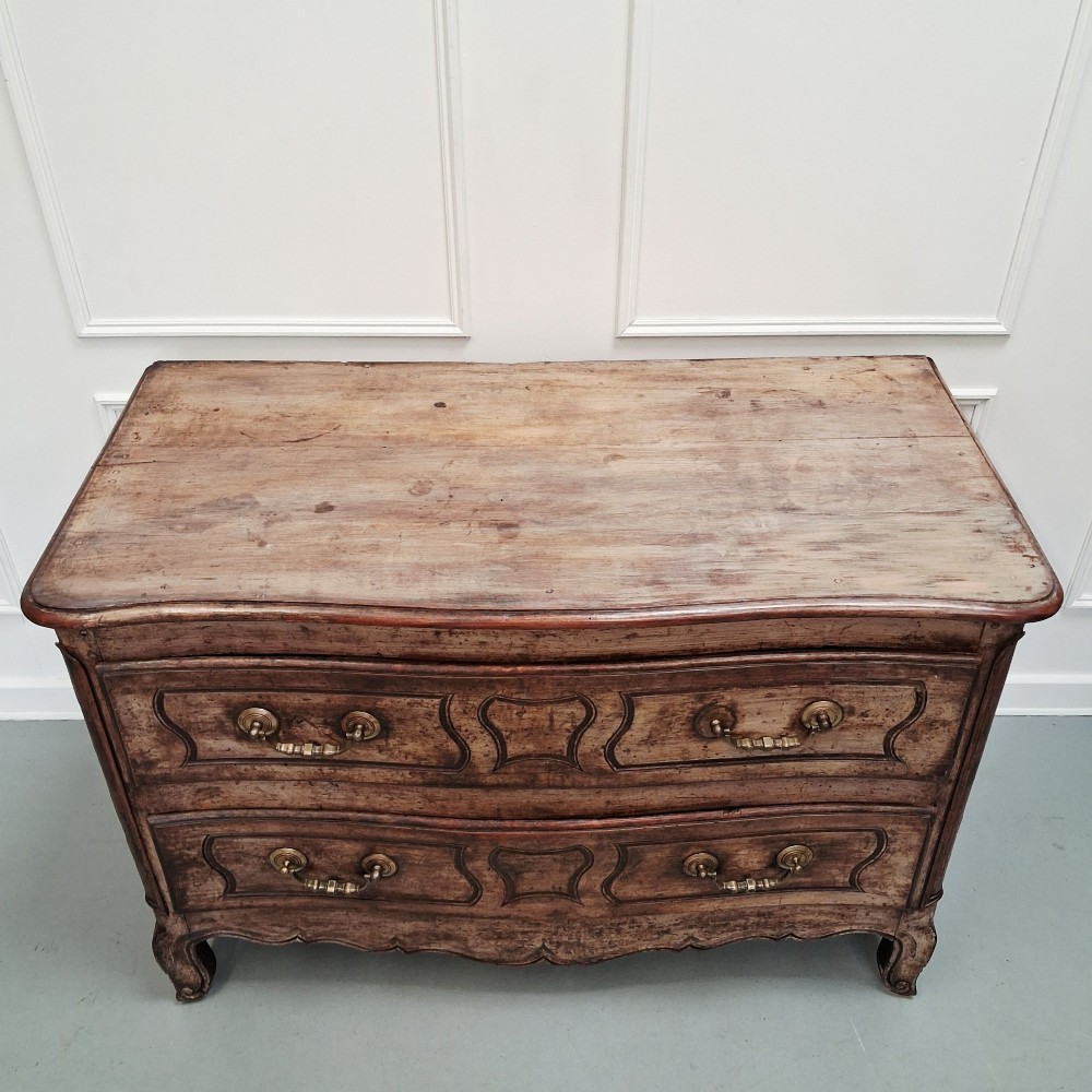 An antique French oak commode featuring two wide drawers with carved moulded panel details, brass drop handles, a scalloped lower apron, and short cabriole feet. View III