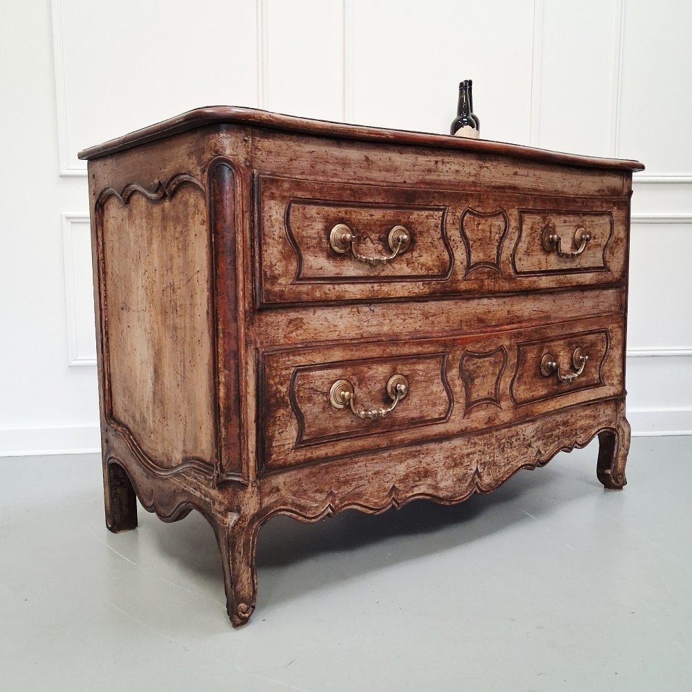 An antique French oak commode featuring two wide drawers with carved moulded panel details, brass drop handles, a scalloped lower apron, and short cabriole feet. View IV