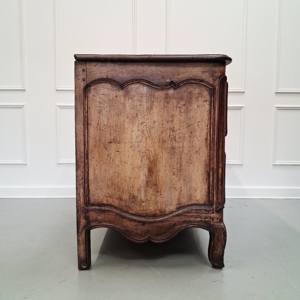 An antique French oak commode featuring two wide drawers with carved moulded panel details, brass drop handles, a scalloped lower apron, and short cabriole feet. View V