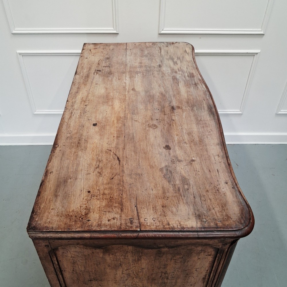 An antique French oak commode featuring two wide drawers with carved moulded panel details, brass drop handles, a scalloped lower apron, and short cabriole feet. View VIII
