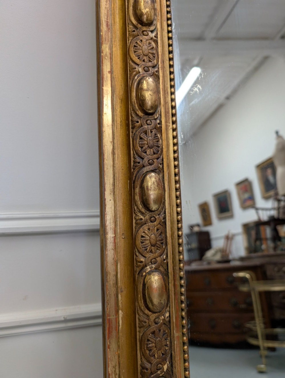 A large nineteenth-century French gilded mirror featuring an arched frame topped with an intricate ribbon crest and beaded border moulding. View III