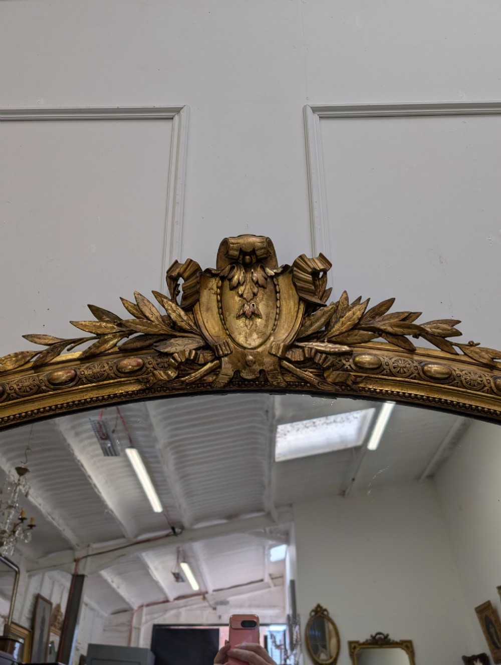 A large nineteenth-century French gilded mirror featuring an arched frame topped with an intricate ribbon crest and beaded border moulding. View IV