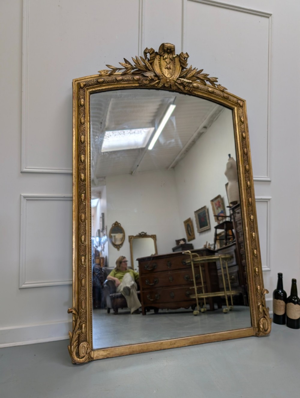 A large nineteenth-century French gilded mirror featuring an arched frame topped with an intricate ribbon crest and beaded border moulding. View VII