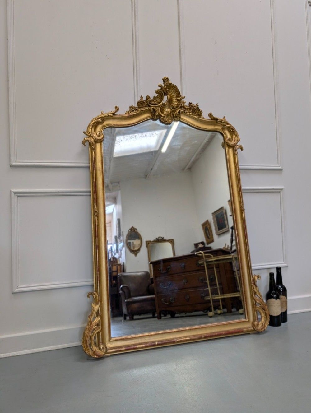 An antique French gilded mirror featuring an ornate Rococo crest with shell and scroll carving along the frame. View II
