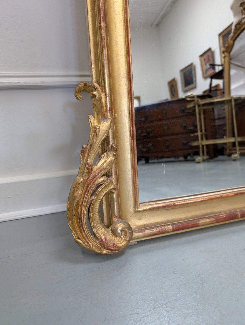 An antique French gilded mirror featuring an ornate Rococo crest with shell and scroll carving along the frame. View III