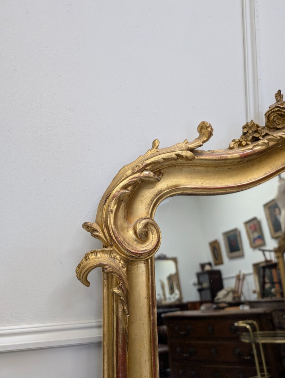 An antique French gilded mirror featuring an ornate Rococo crest with shell and scroll carving along the frame. View IV