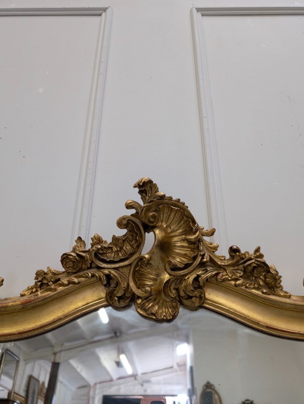 An antique French gilded mirror featuring an ornate Rococo crest with shell and scroll carving along the frame. View V