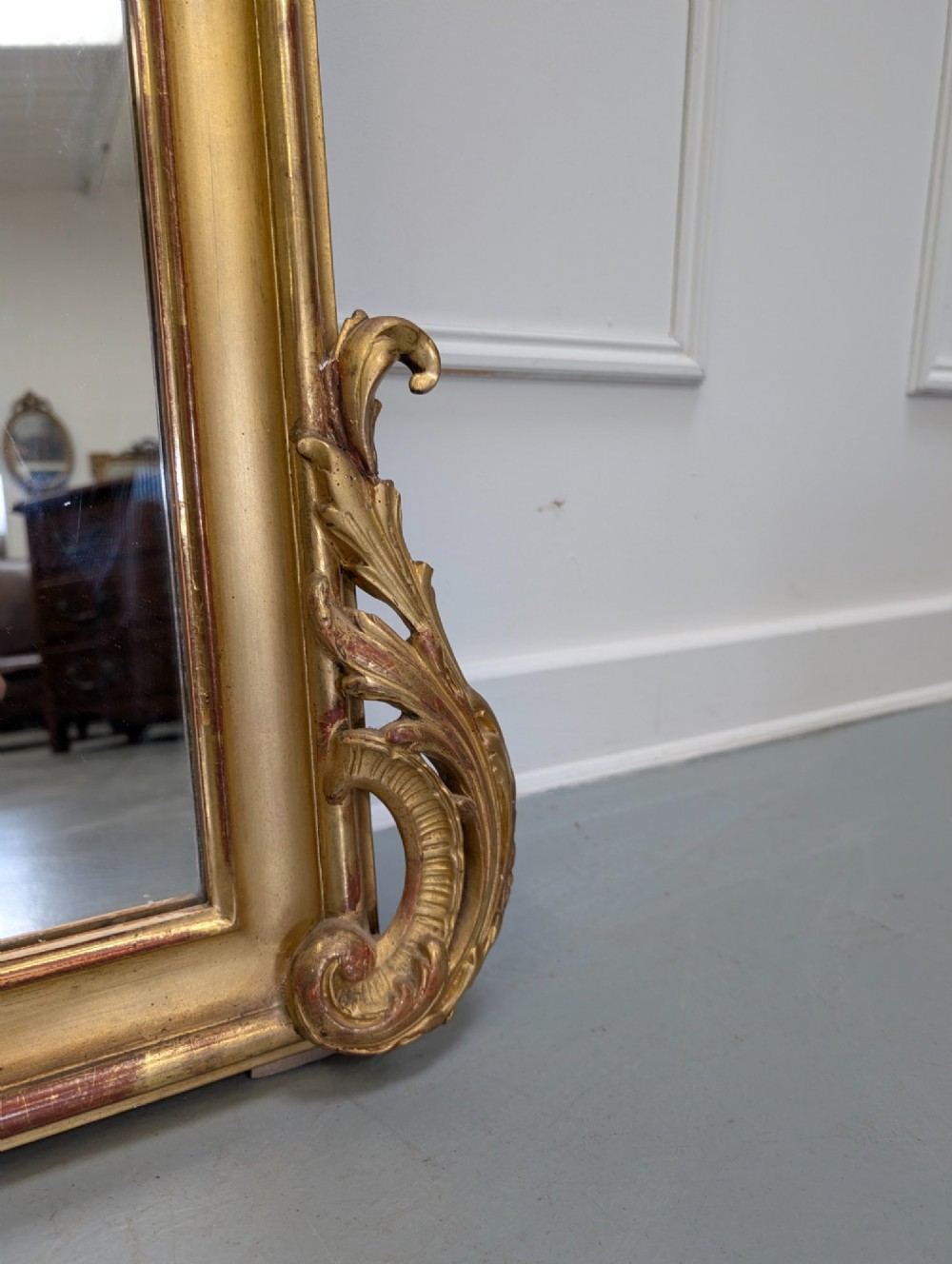 An antique French gilded mirror featuring an ornate Rococo crest with shell and scroll carving along the frame. View VI
