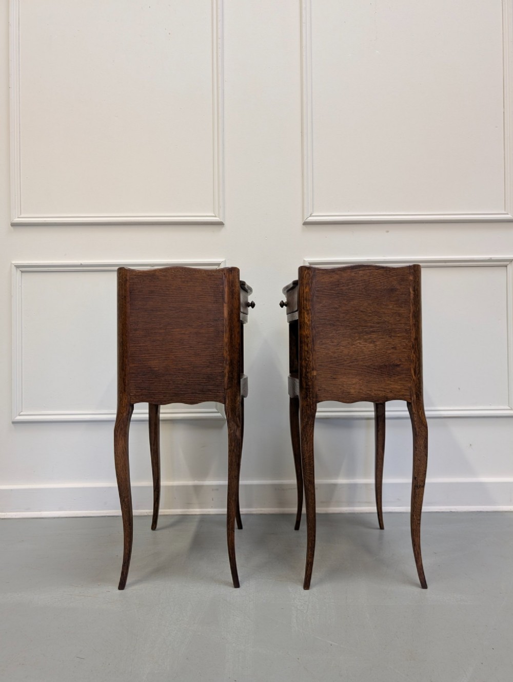 A pair of French dark oak bedside tables featuring slender cabriole legs, an open shelf alcove, and a single drawer with a metal knob. View II