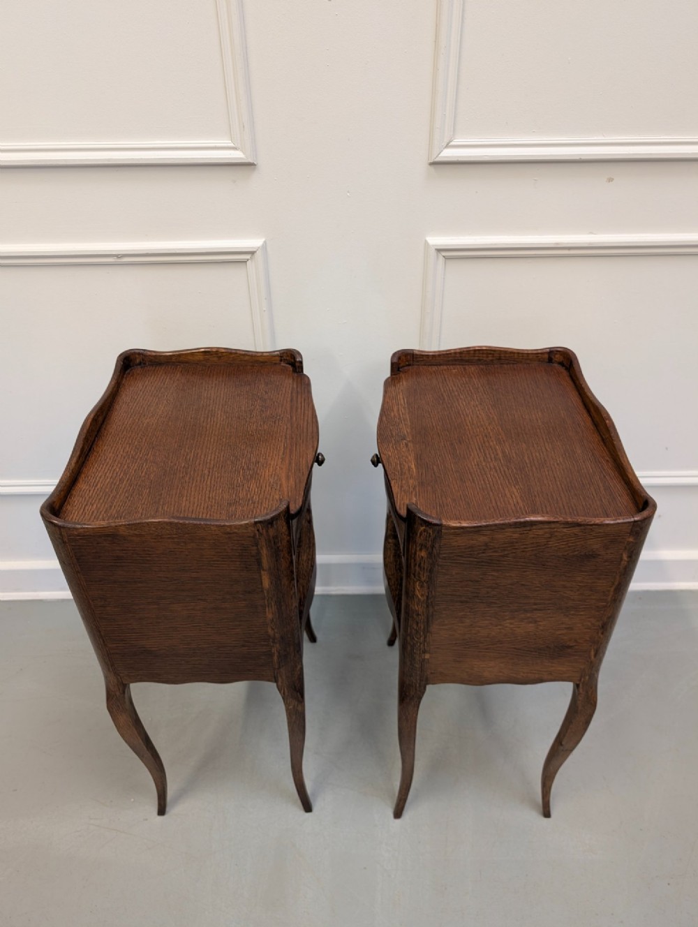 A pair of French dark oak bedside tables featuring slender cabriole legs, an open shelf alcove, and a single drawer with a metal knob. View III