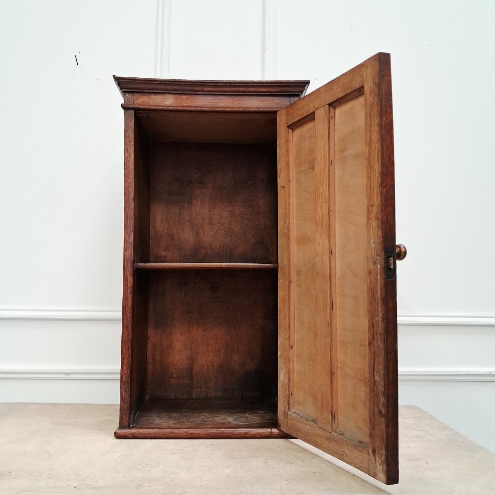 An antique medium brown oak wall cupboard featuring a panelled single door with Clean Towels in gilt lettering across the top and a brass door knob. View III