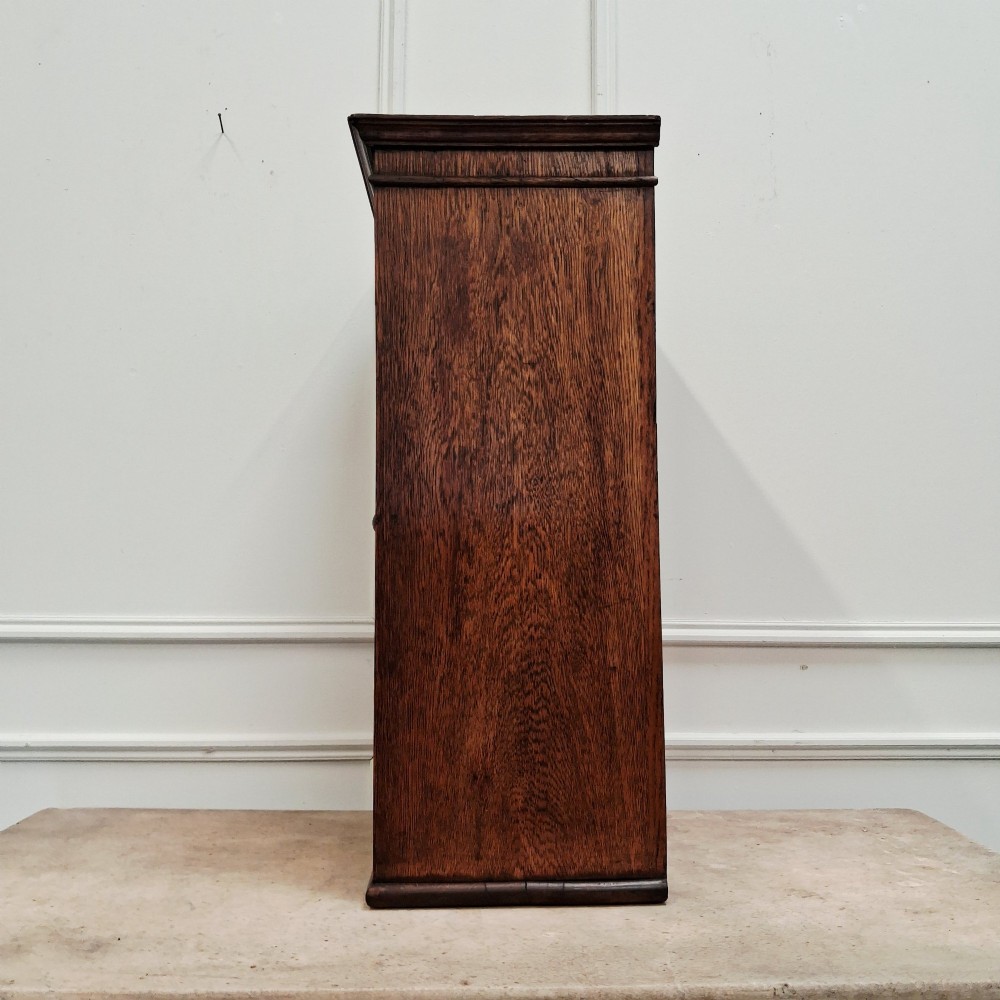 An antique medium brown oak wall cupboard featuring a panelled single door with Clean Towels in gilt lettering across the top and a brass door knob. View VI