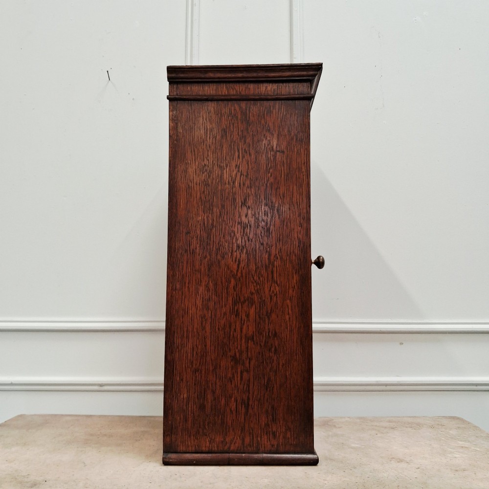 An antique medium brown oak wall cupboard featuring a panelled single door with Clean Towels in gilt lettering across the top and a brass door knob. View VIII