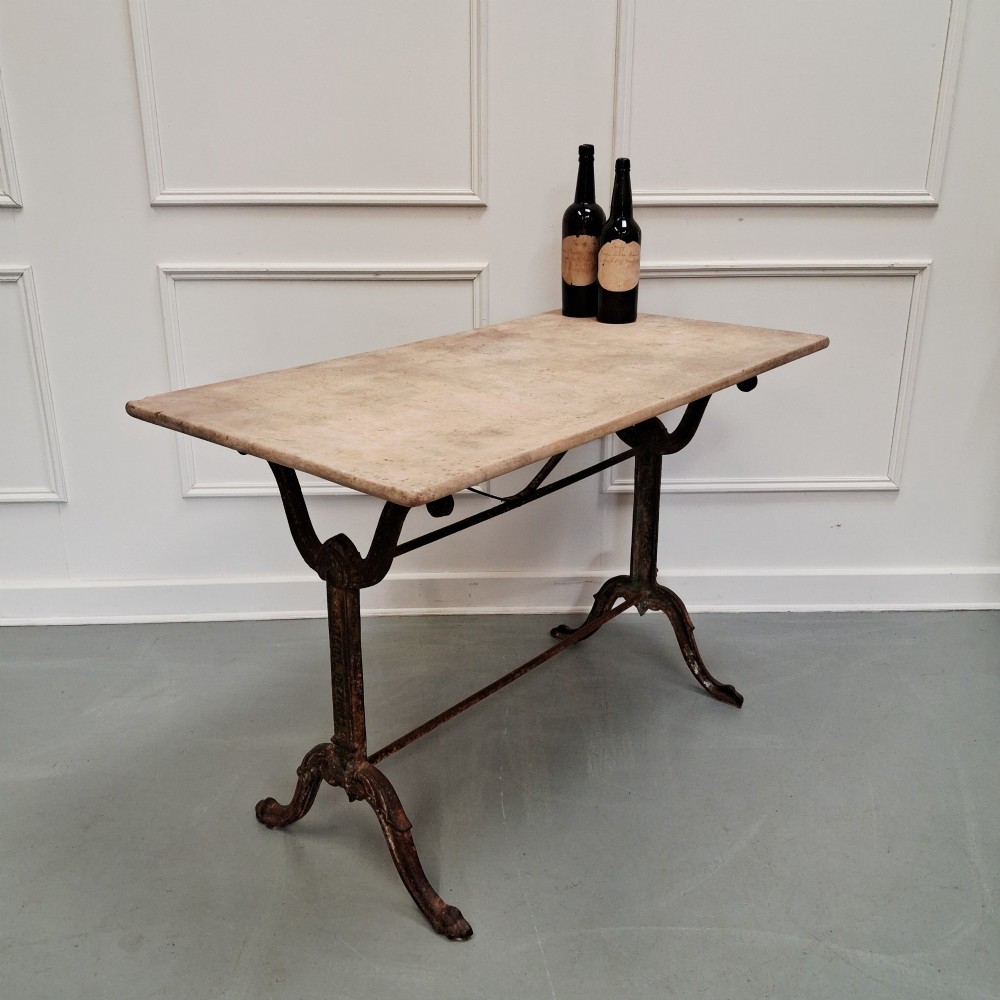A rectangular off-white marble top bistro table supported by a dark weathered cast iron frame with scrolled legs and stretchers. View V
