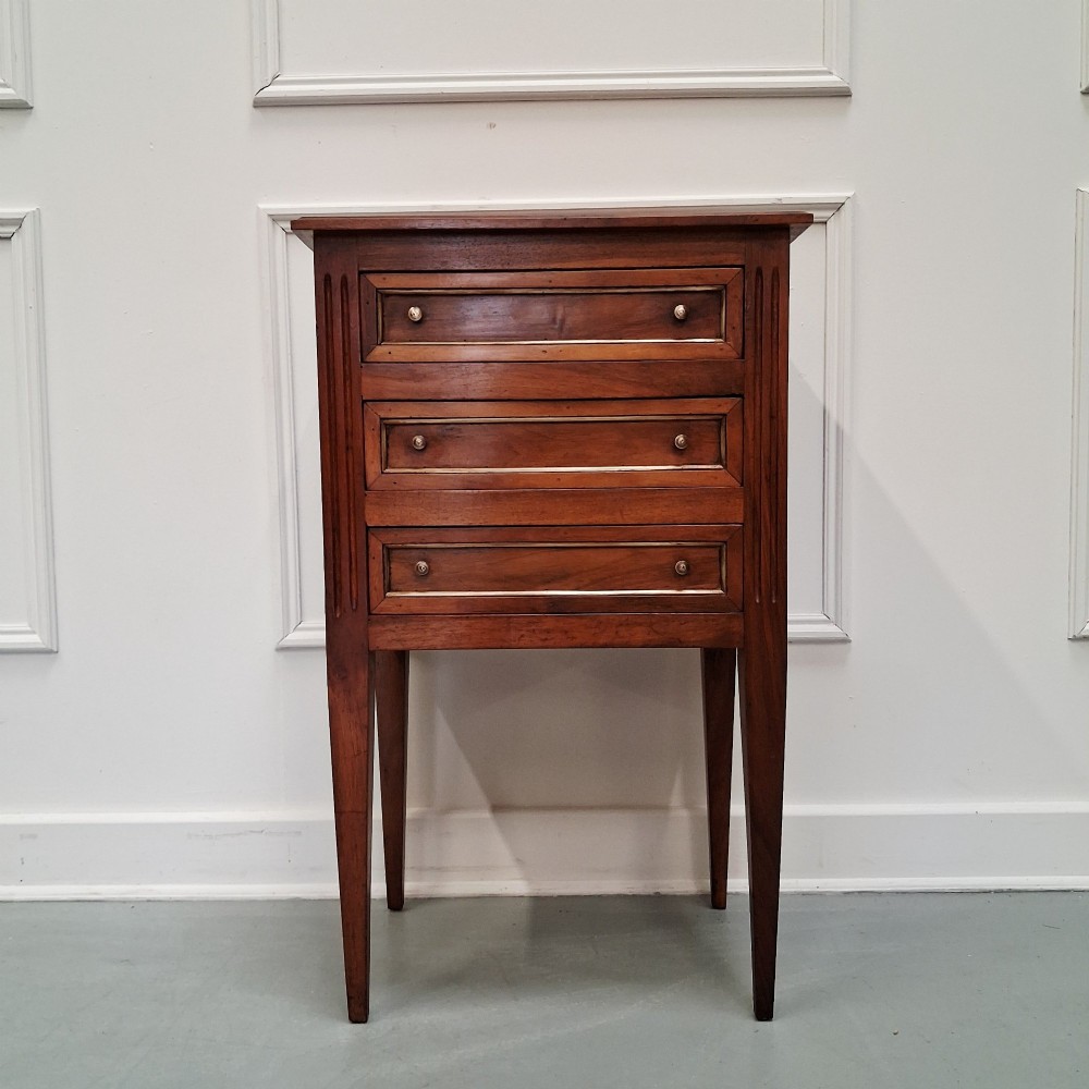 A pair of French antique walnut bedside tables with three drawers and slender tapered legs. View IX